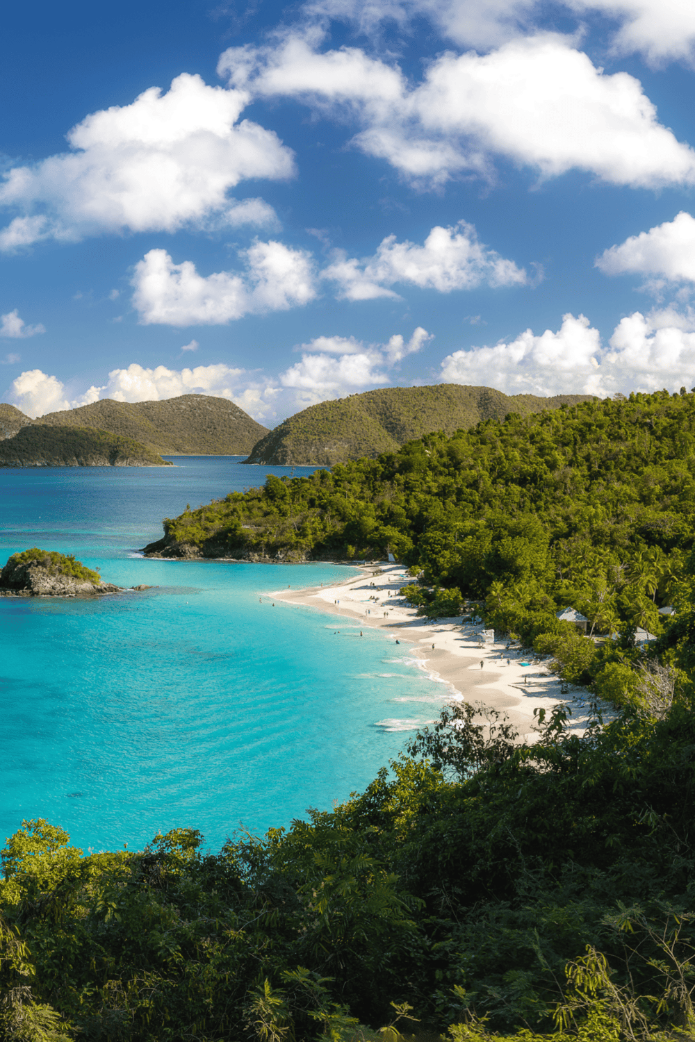 Pristine tropical beach with turquoise waters, lush greenery, and mountainous backdrop, perfect for vacation and travel.