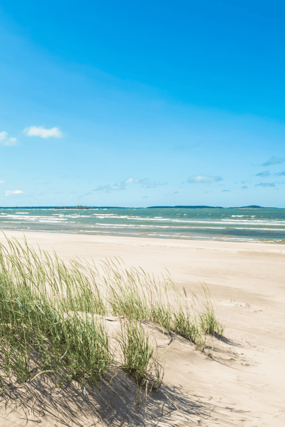 Tranquil beach with sandy shores, blue sky, and gentle ocean waves, perfect for travel and vacation planning.
