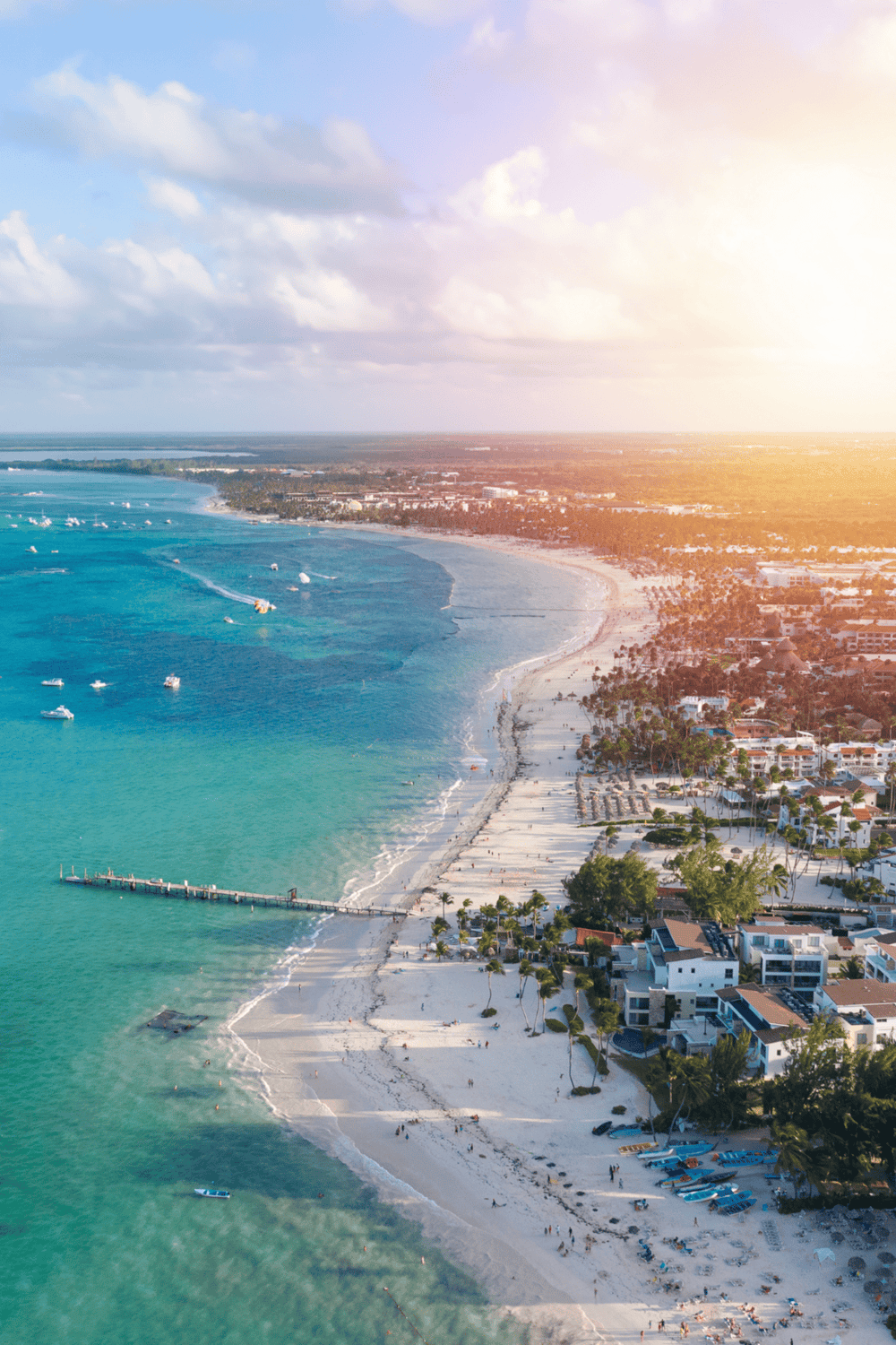 Vibrant beach coastline with boats, palm trees, and scenic ocean views at sunset.