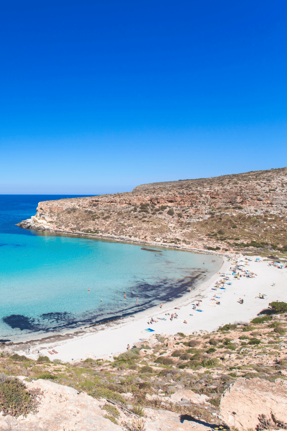 Secluded beach with turquoise waters, rocky cliffs, and scenic coastline in a travel destination.