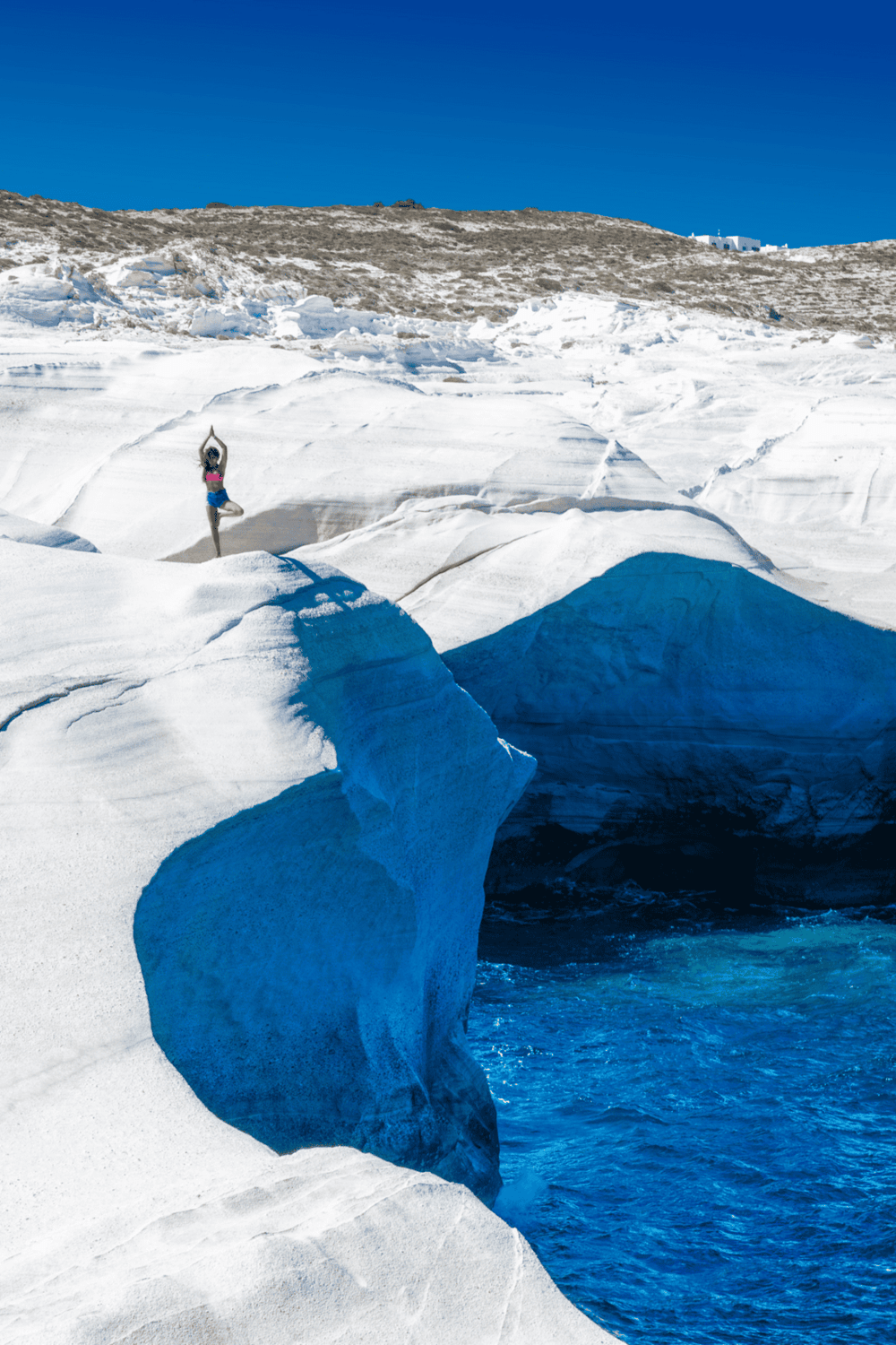 Serene woman practicing yoga on icy glacier under clear blue sky, inspiring outdoor adventure and wellness.
