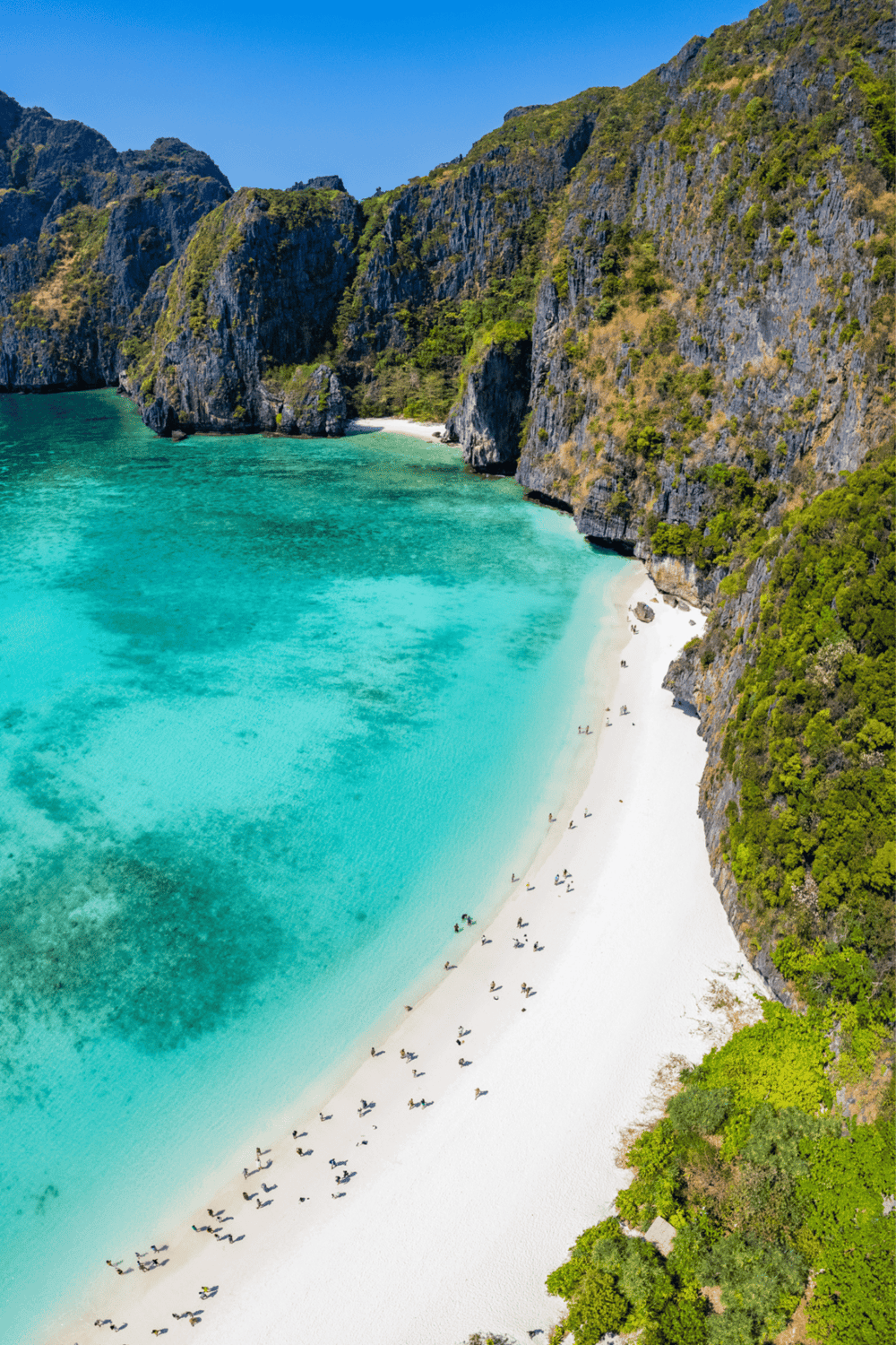 Pristine tropical beach with turquoise waters and dramatic limestone cliffs, perfect for travel and adventure.