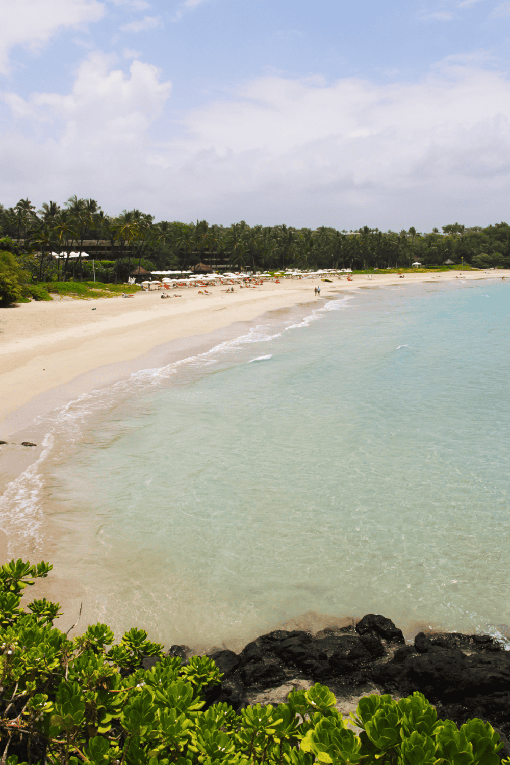 - Pristine beach with turquoise waters and lush tropical greenery in the background.