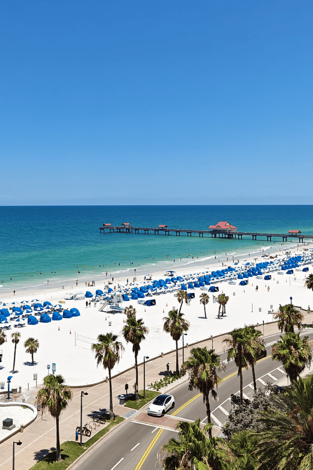 Sunny beach with white sand and blue umbrellas in Florida’s destination guide.