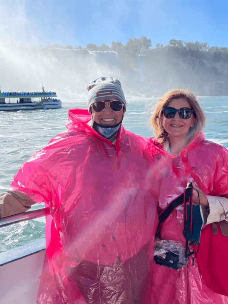 Colorful tour guides at Niagara Falls with sightseeing boat, wearing pink rain ponchos.
