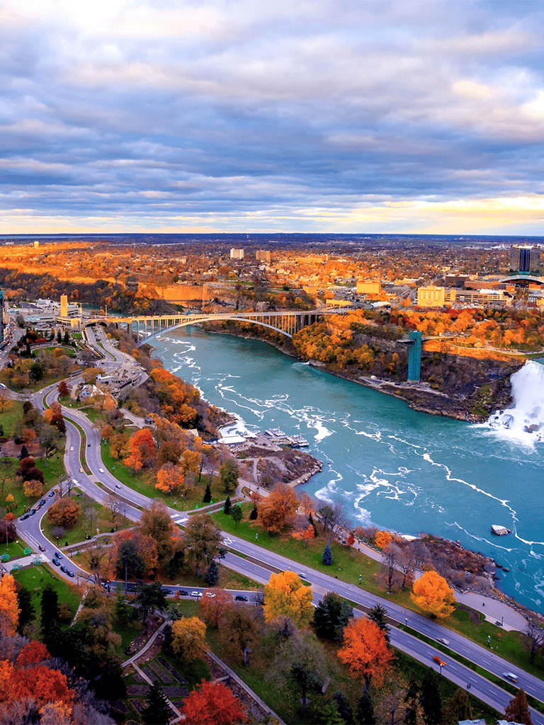 Vibrant autumn view of Niagara Falls and surrounding cityscape during sunset.