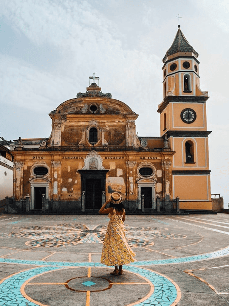 Colorful historic church facade with a woman in a yellow dress in front, vibrant travel destination, picturesque architecture.