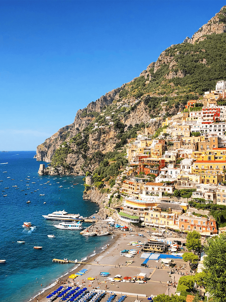 Colorful coastal town with houses on steep cliffs and a busy beach scene in Italy.
