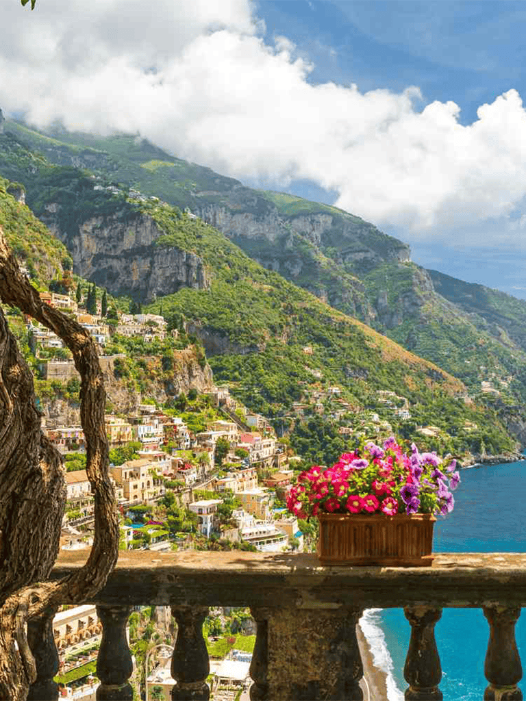 Breathtaking coastal village on Italy's Amalfi Coast with colorful flowers and scenic mountain views.
