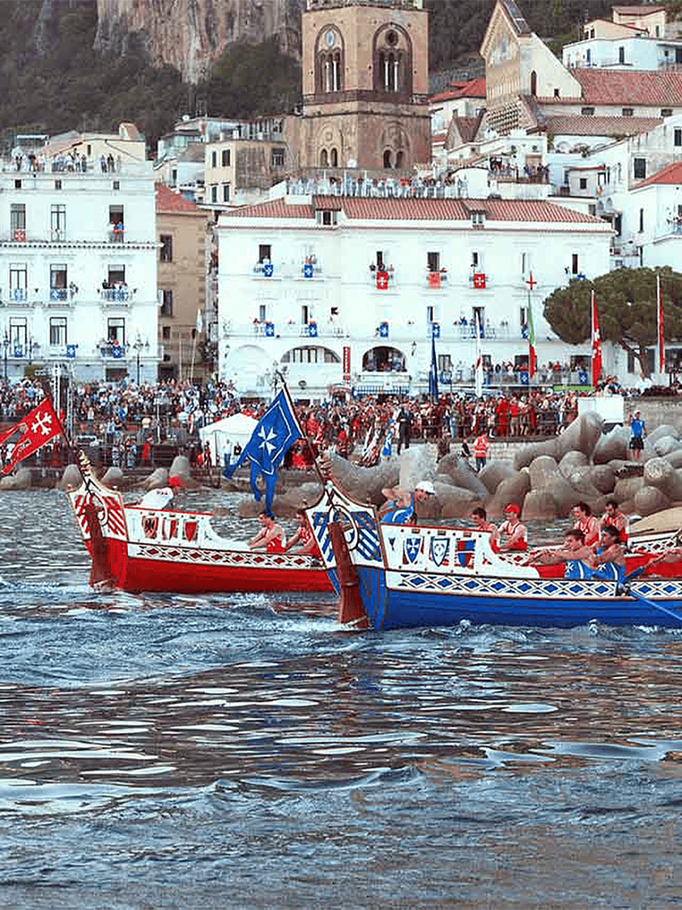 Colorful historical boats participating in a traditional regatta along a scenic coastal town.