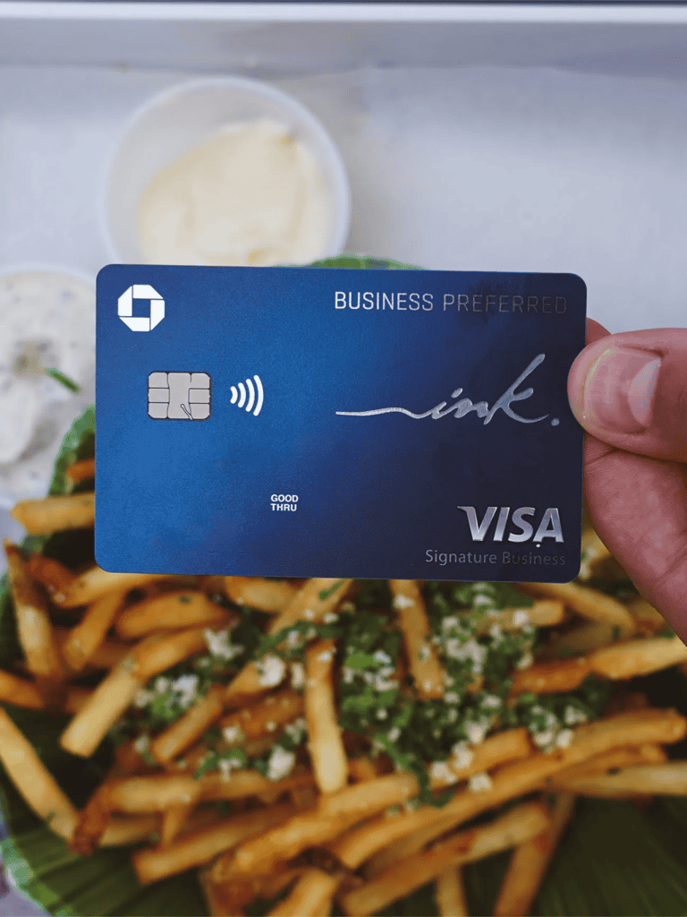 Credit card with business preferred label and Visa logo over food dish with pasta and sauces.