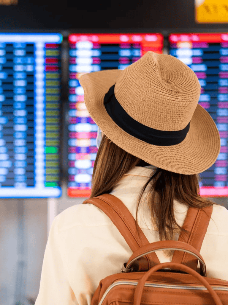 1. Woman at airport terminal viewing flight departure board with travel directions.
