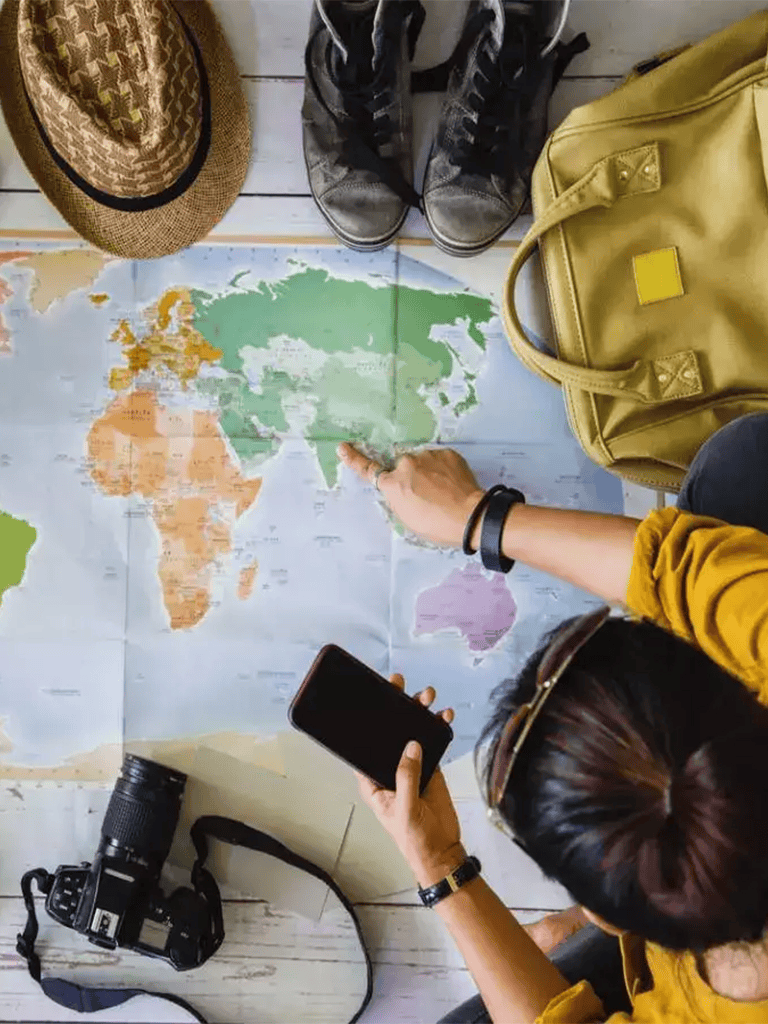 World map travel planning with smartphone and camera, travel accessories, and suitcase, travel destination planning, explore different countries and cultures.