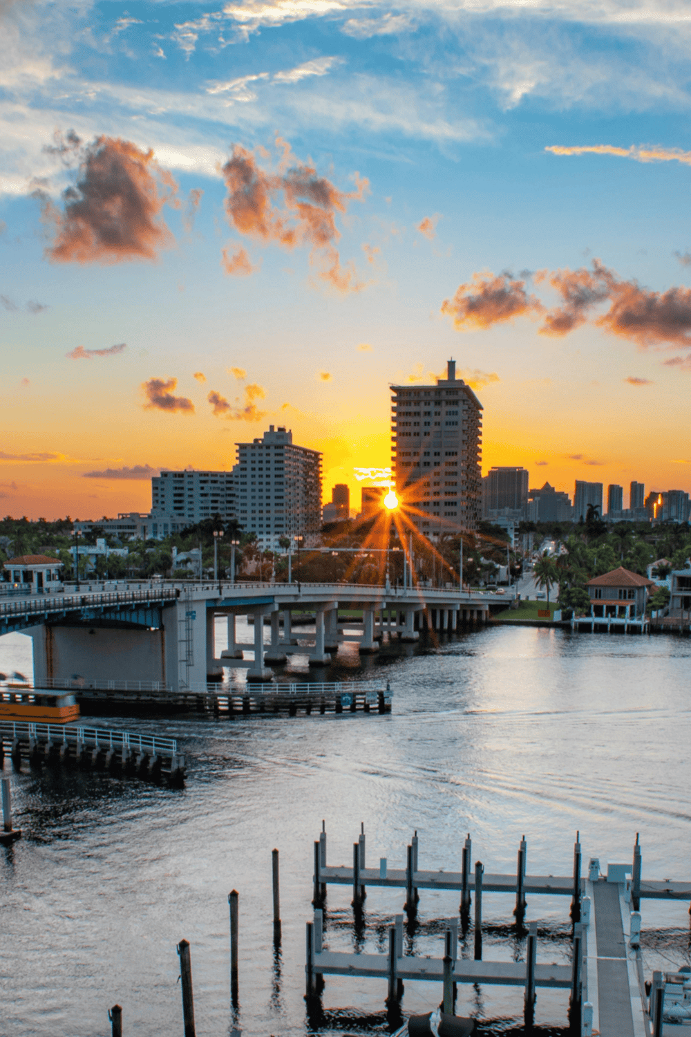 Sunset over Miami skyline with waterway and bridge, vibrant evening scenery in Florida.