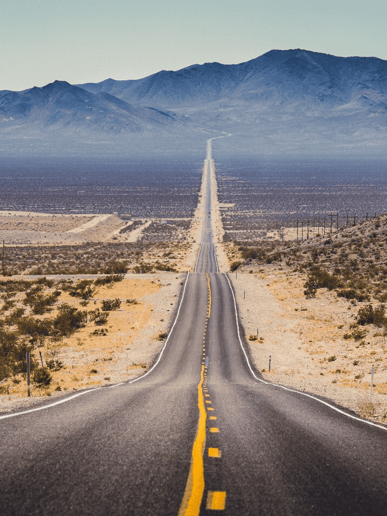 Desert highway stretching to mountains in the distance, symbolizing travel and adventure.