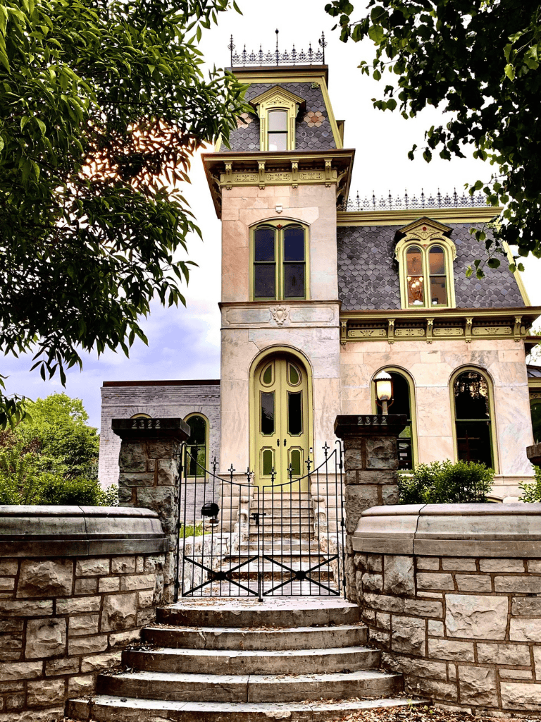 Victorian-style house with ornate details and lush greenery, perfect for home navigation and real estate searches.