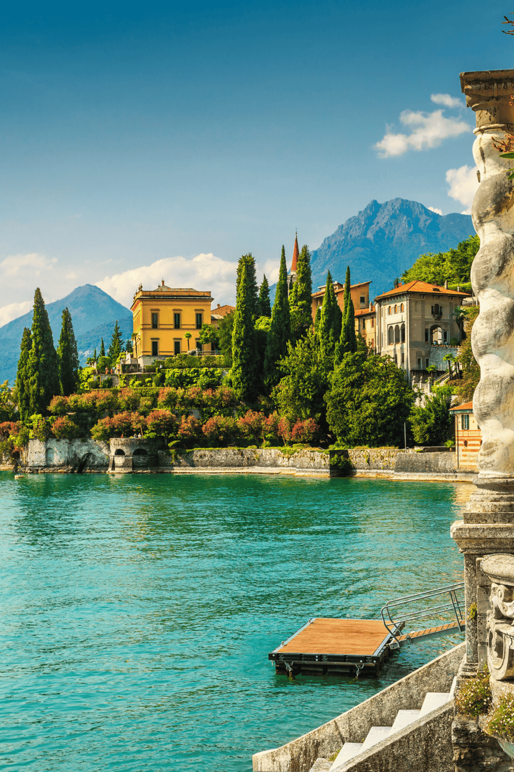 Stunning lakeside villa with lush greenery and mountain backdrop in Italy’s scenic region.