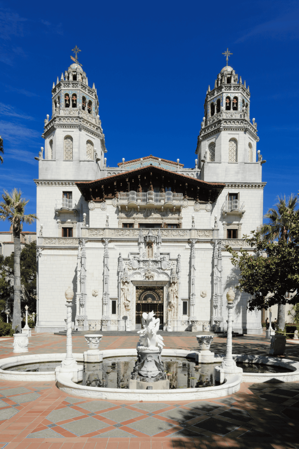 Intricate white Spanish-style church with twin bell towers under blue sky.