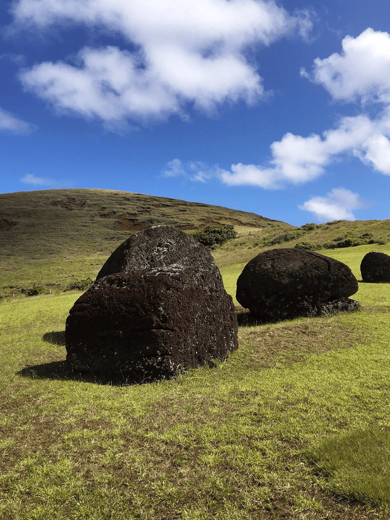 Ancient volcanic rocks in lush green landscape under blue sky, outdoors in a scenic natural setting.