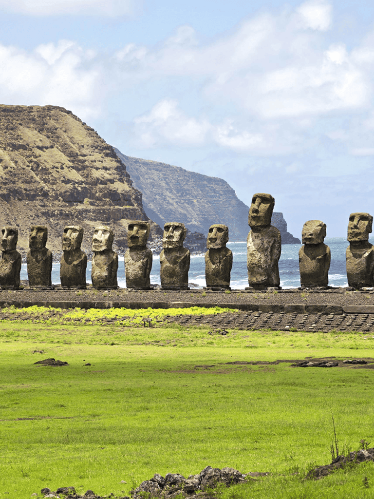 Ancient Moai statues on Easter Island with scenic cliffs and ocean backdrop.