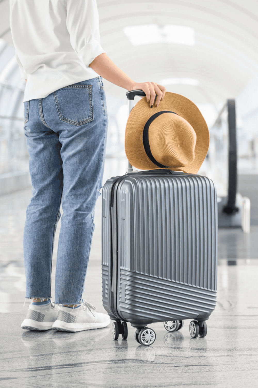 Comfortable travel luggage with hat at airport terminal.