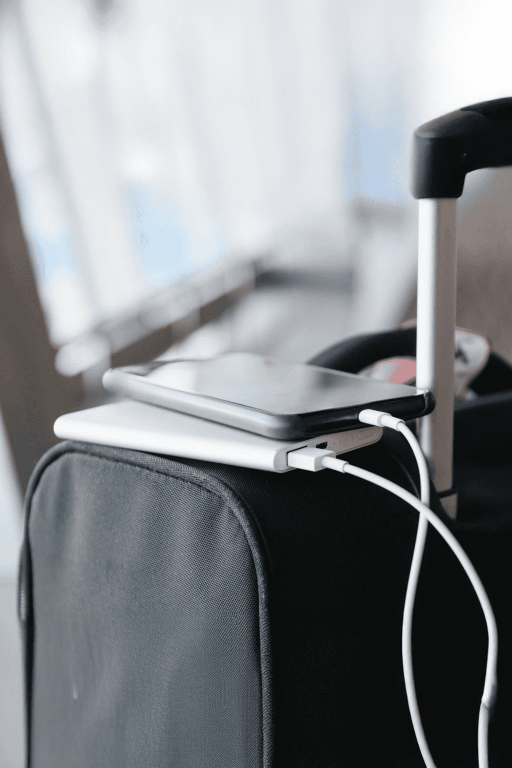 Wireless charging on portable luggage with smartphone and charging cable.