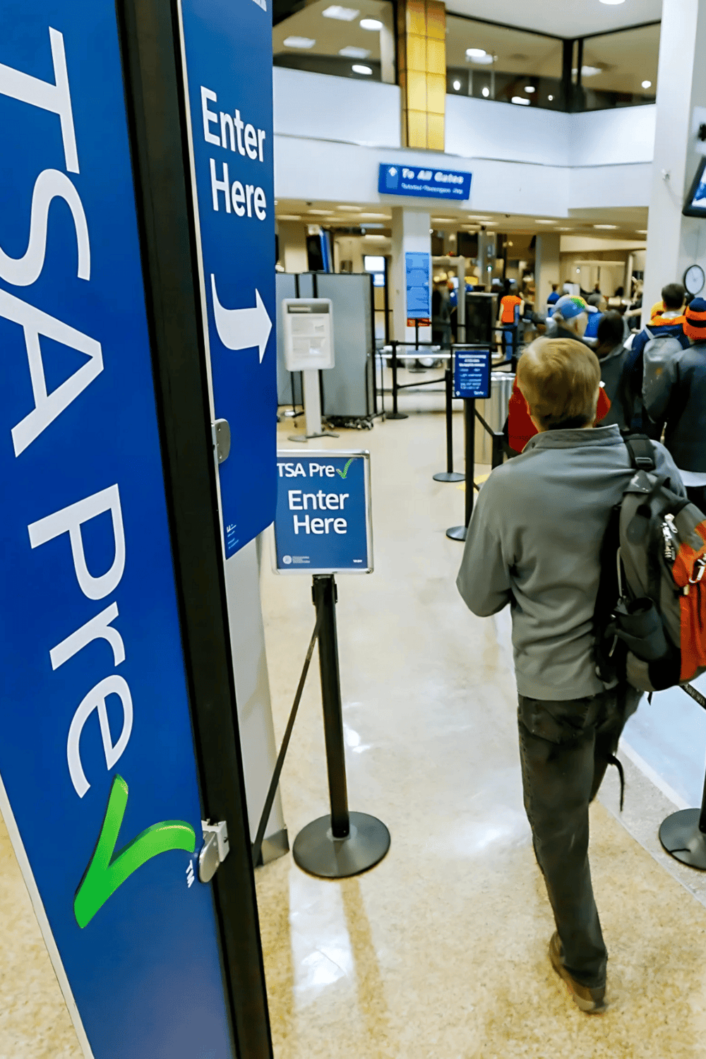 1. TSA PreCheck entrance sign at airport security checkpoint with travelers waiting in line.