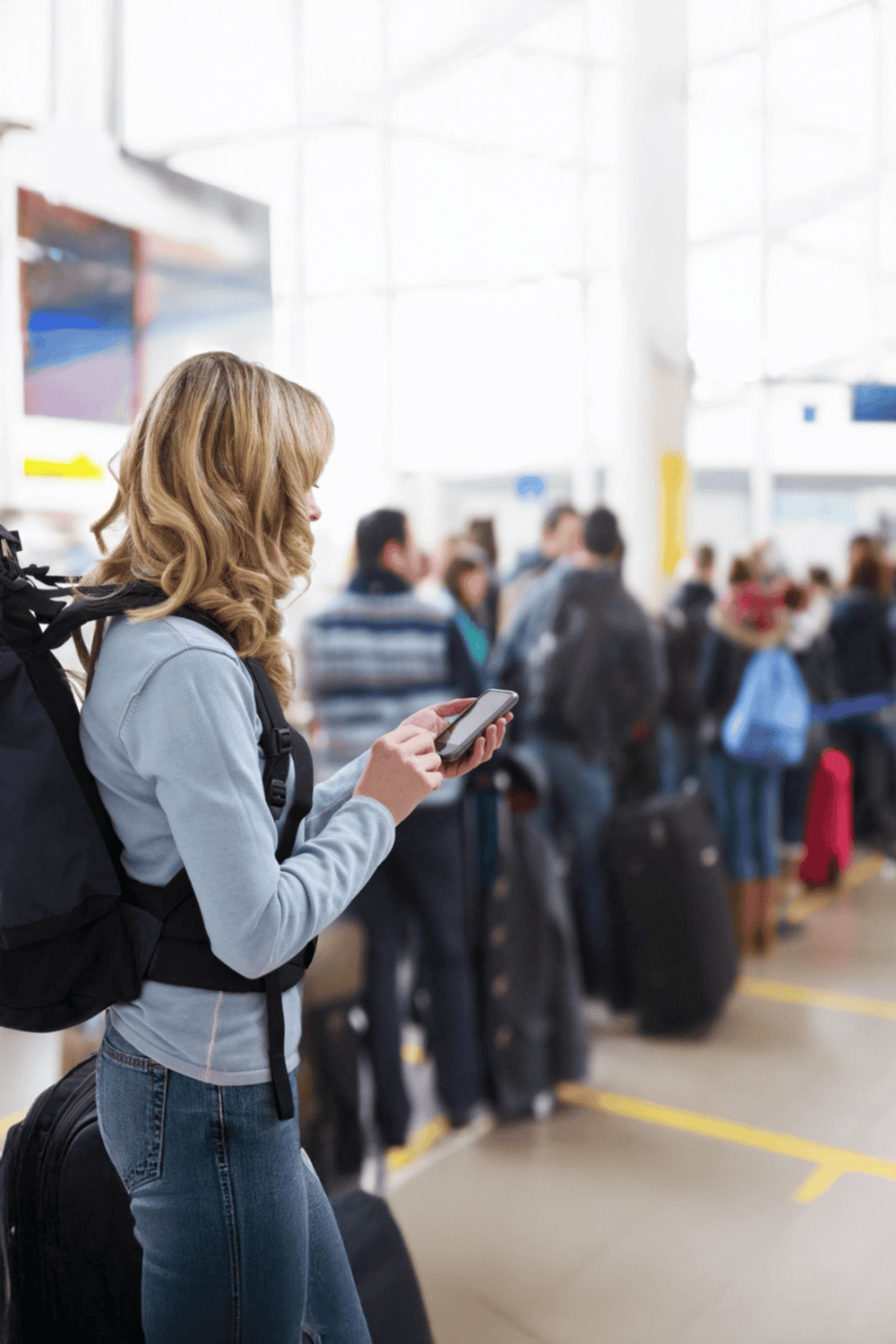 Busy woman at airport using smartphone for travel directions.