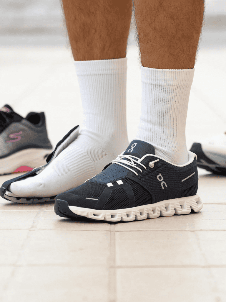 Running shoes with white socks on wooden floor, sporty footwear for active lifestyle.
