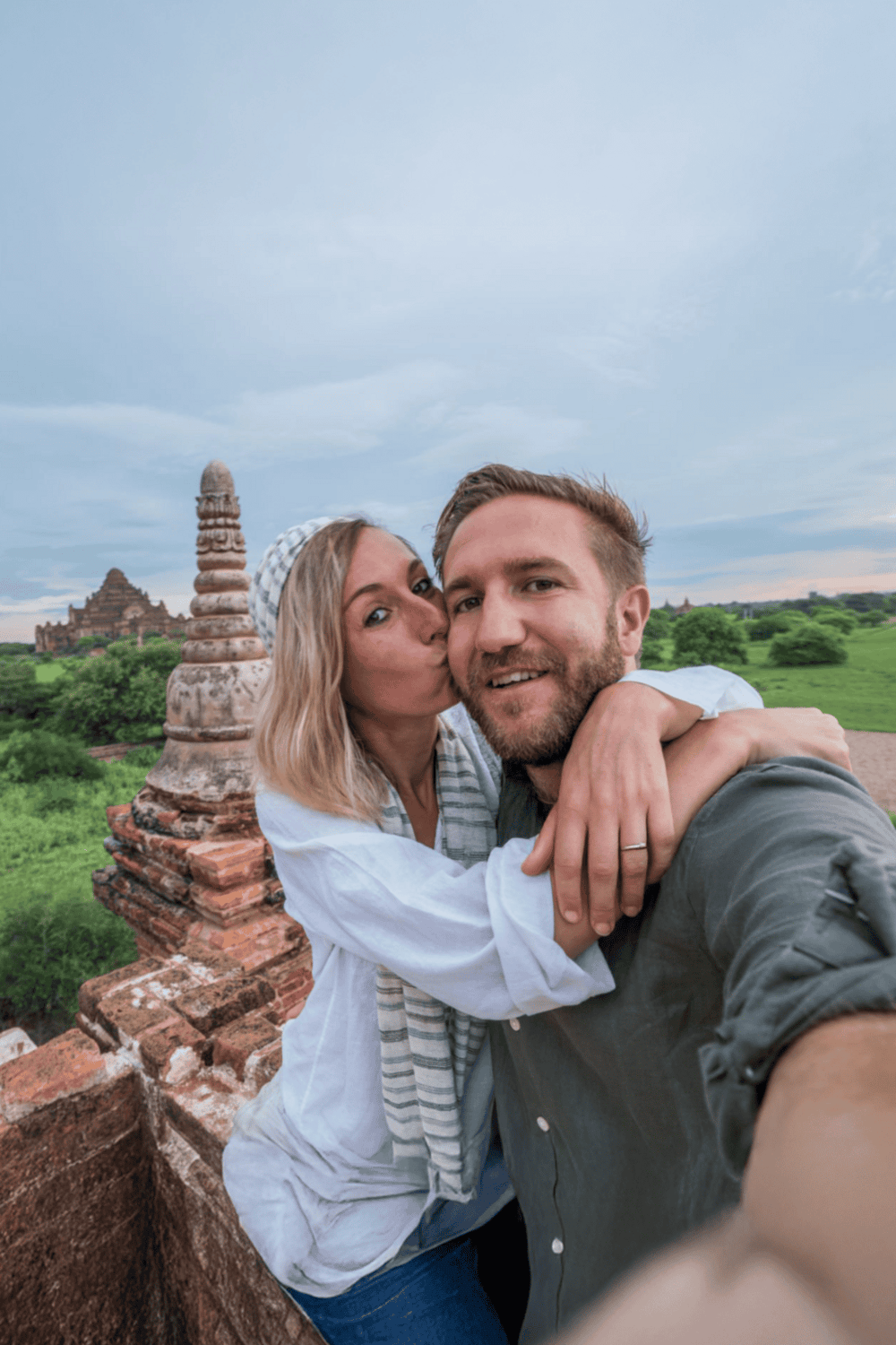 Beautiful couple taking a selfie at ancient temple ruins in Thailand, showcasing travel, exploration, and cultural adventures.