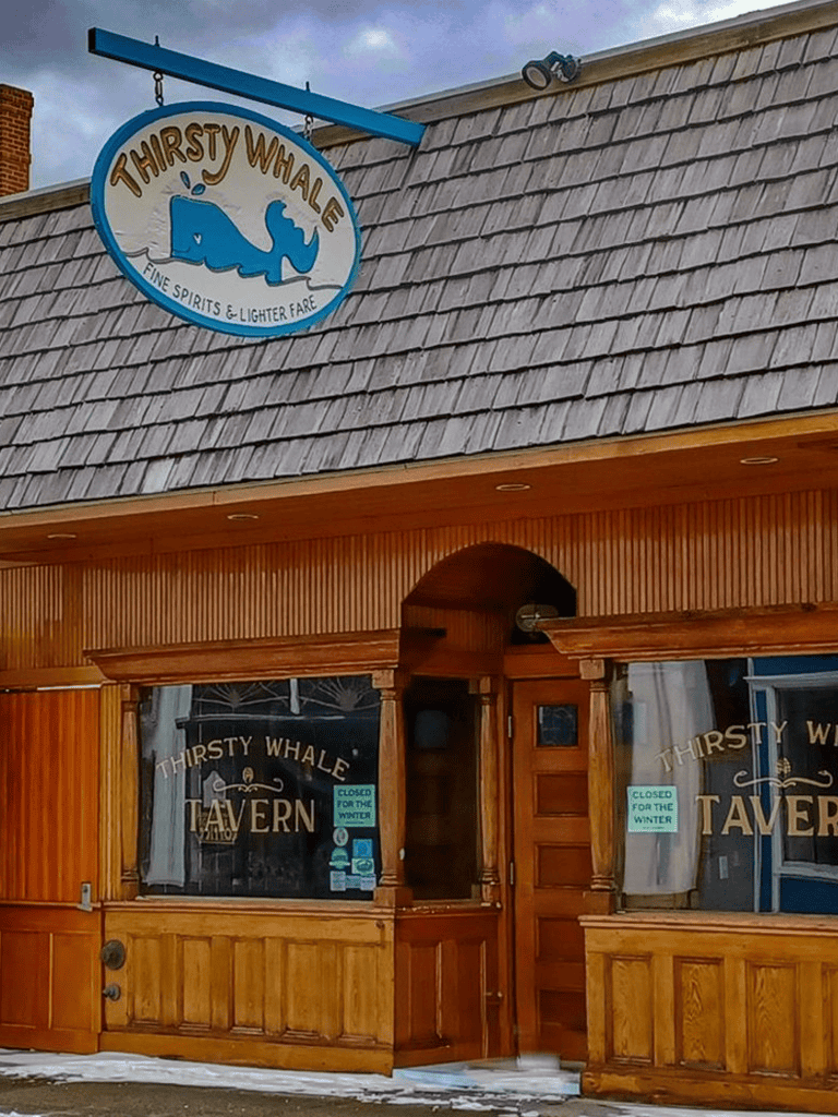 Whale-themed bar or tavern with "Thirsty Whale" signage and cozy wooden exterior.