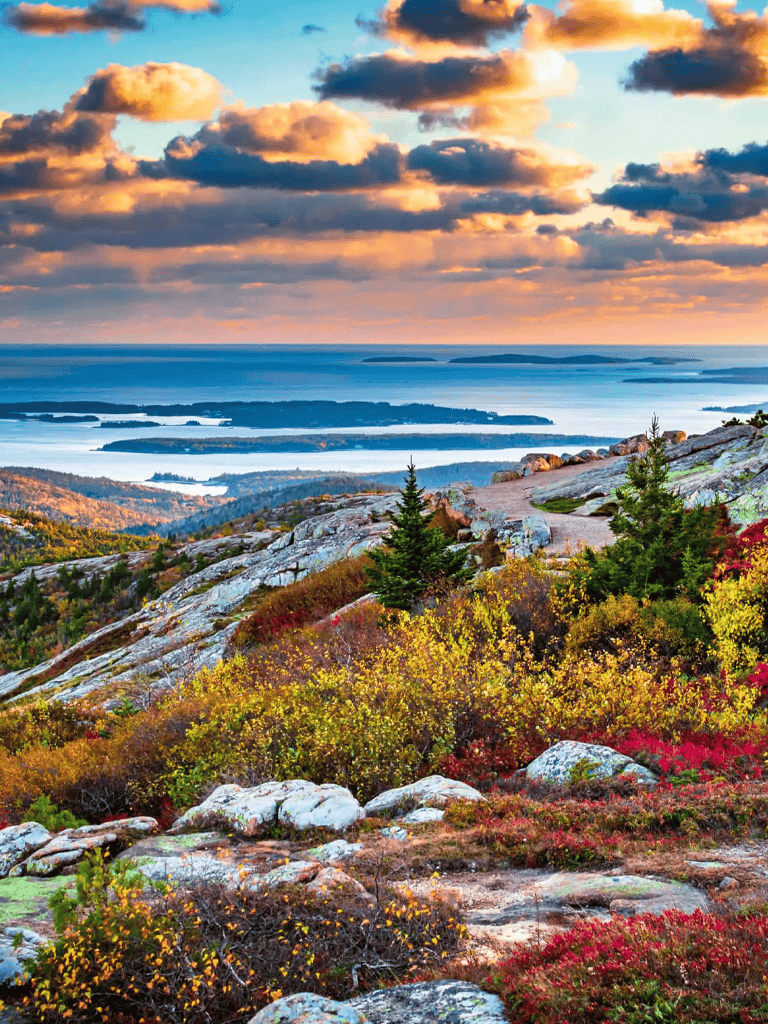 Vivid autumn landscape with colorful foliage, rocky terrain, and scenic lake views at sunset.