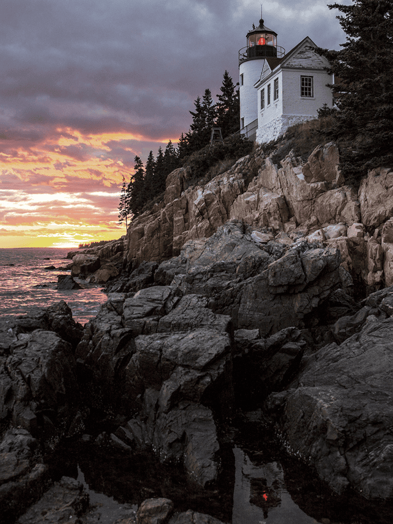 Lighthouse on rocky coastline at sunset, scenic coastal navigation, QuestForDirections.