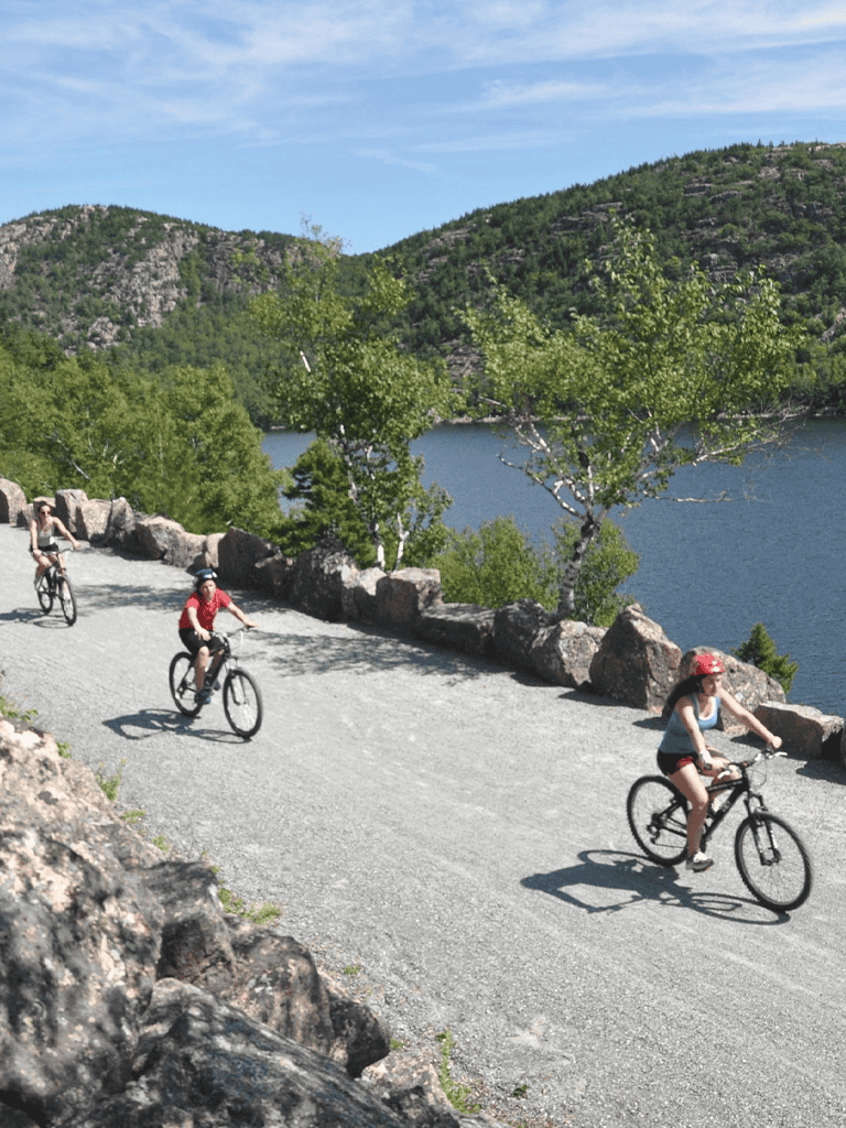 Bicycle riders on scenic lakeside trail with green mountains and blue sky, outdoor recreation, nature adventure, QuestForDirections.