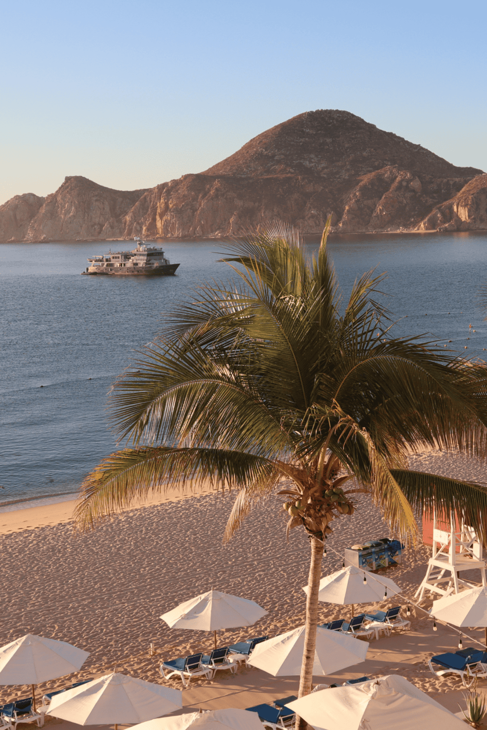 Seaside yacht cruising view with palm trees and sandy beach at sunset, ideal for travel and vacation planning.