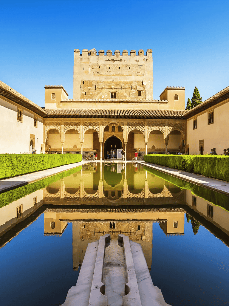 Ancient fortress with reflective pool and lush greenery, Moorish architecture, Granada, Spain.