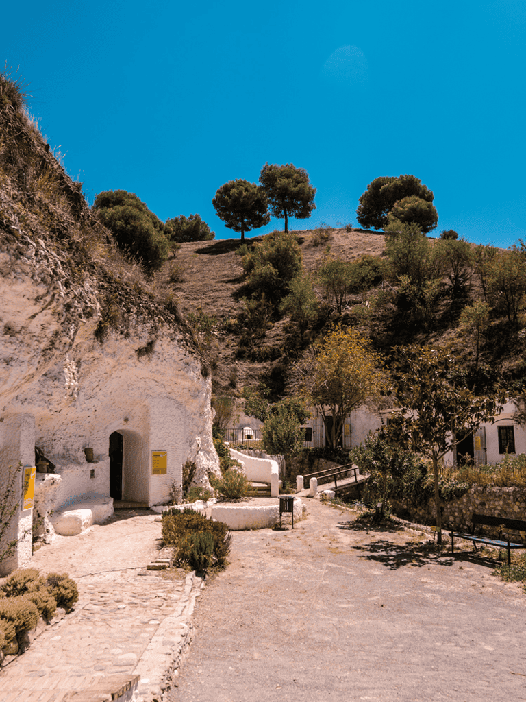 Quiet hillside village with white cave houses, lush greenery, and scenic views, perfect for travel and exploration.