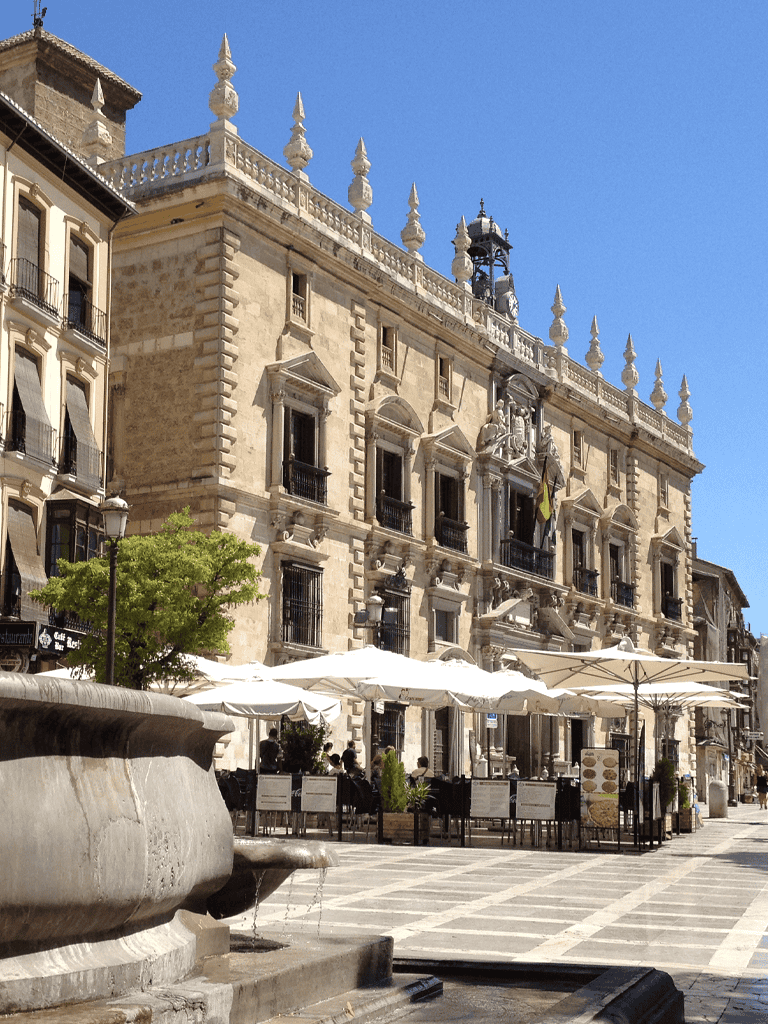 Elegant historic city hall building in Madrid, Spain with outdoor seating and clear blue sky, showcasing architectural beauty and vibrant city life.