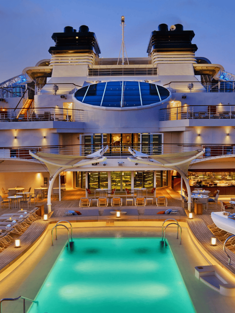 Luxurious cruise ship with rooftop pool and panoramic views at sunset.