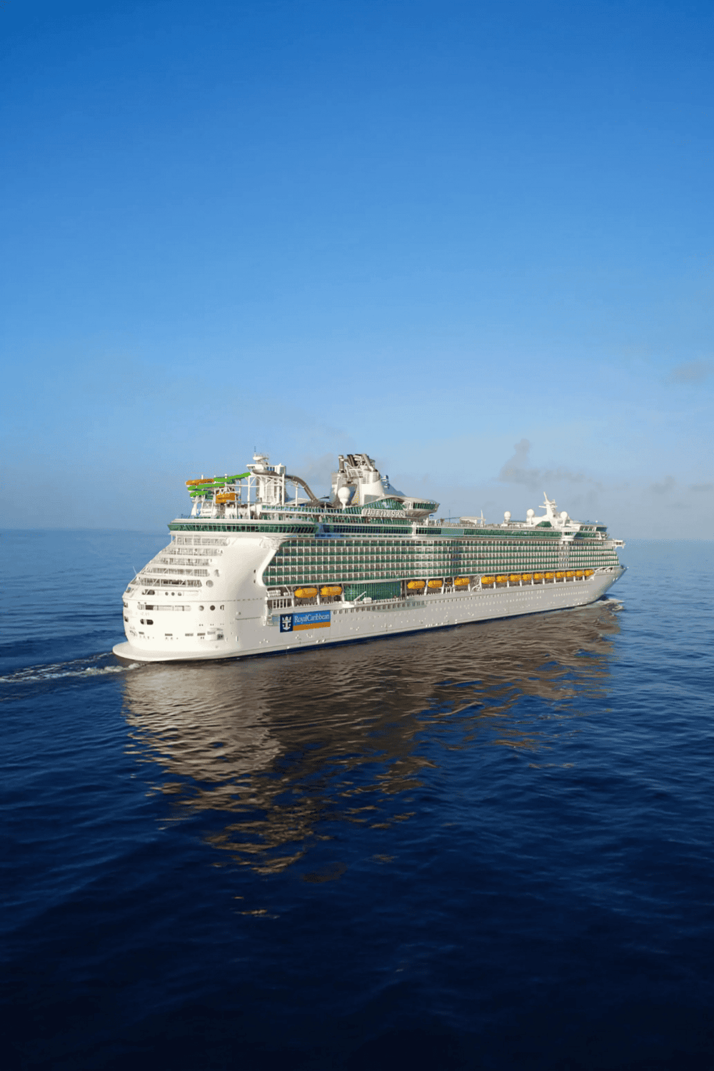 Luxury cruise ship navigating open ocean with clear blue sky, part of QuestForDirections travel services.