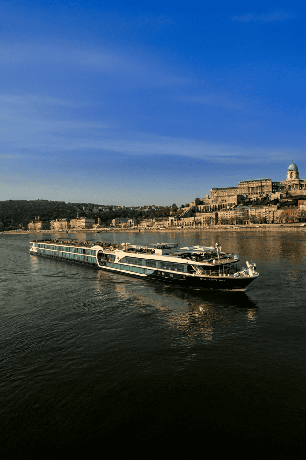 Cruise ship on river with historic cityscape and castle in the background, scenic view for travel and tourism.