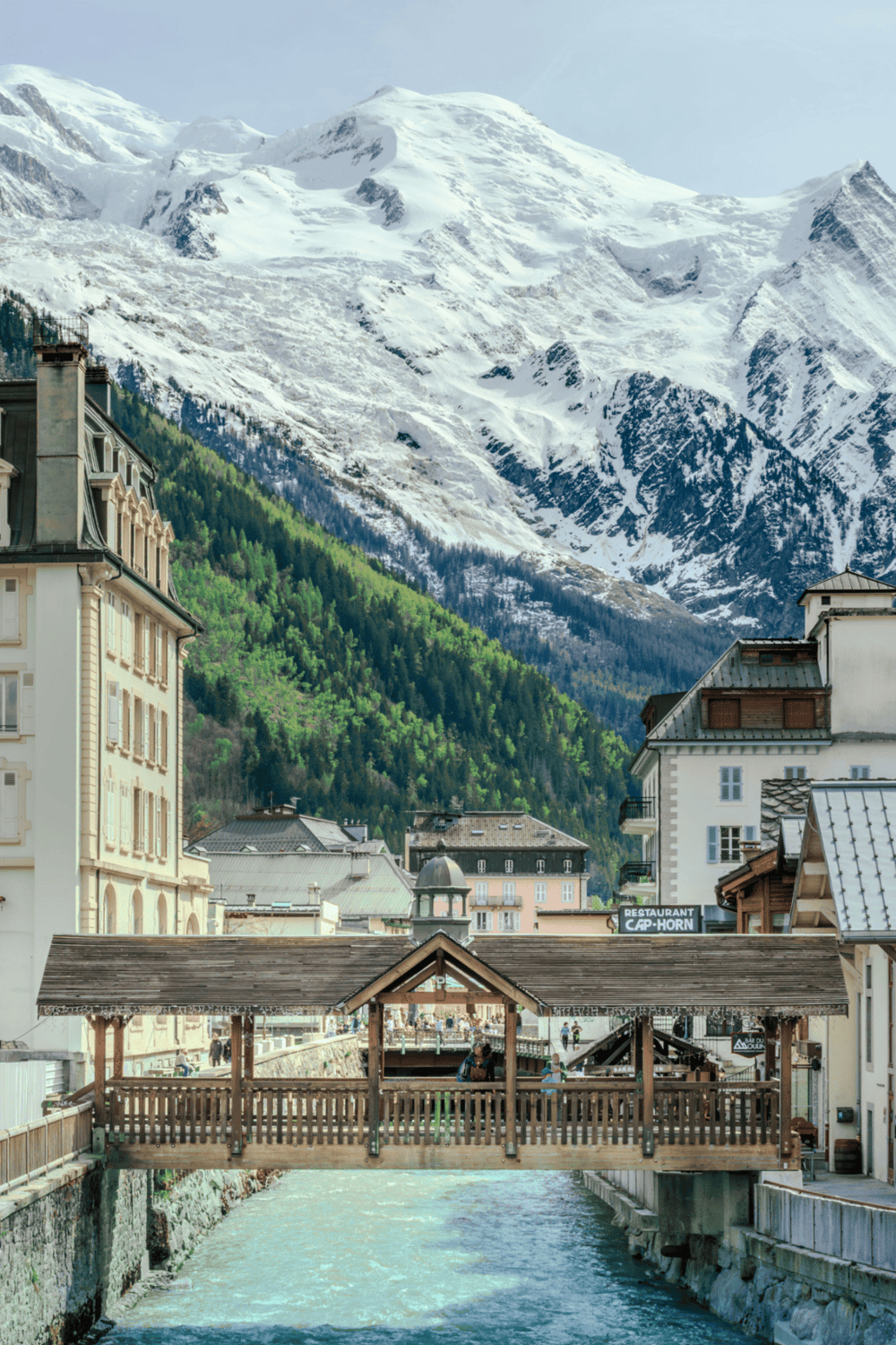 Snow-capped mountains and charming Alpine town with riverfront cafés in Switzerland.