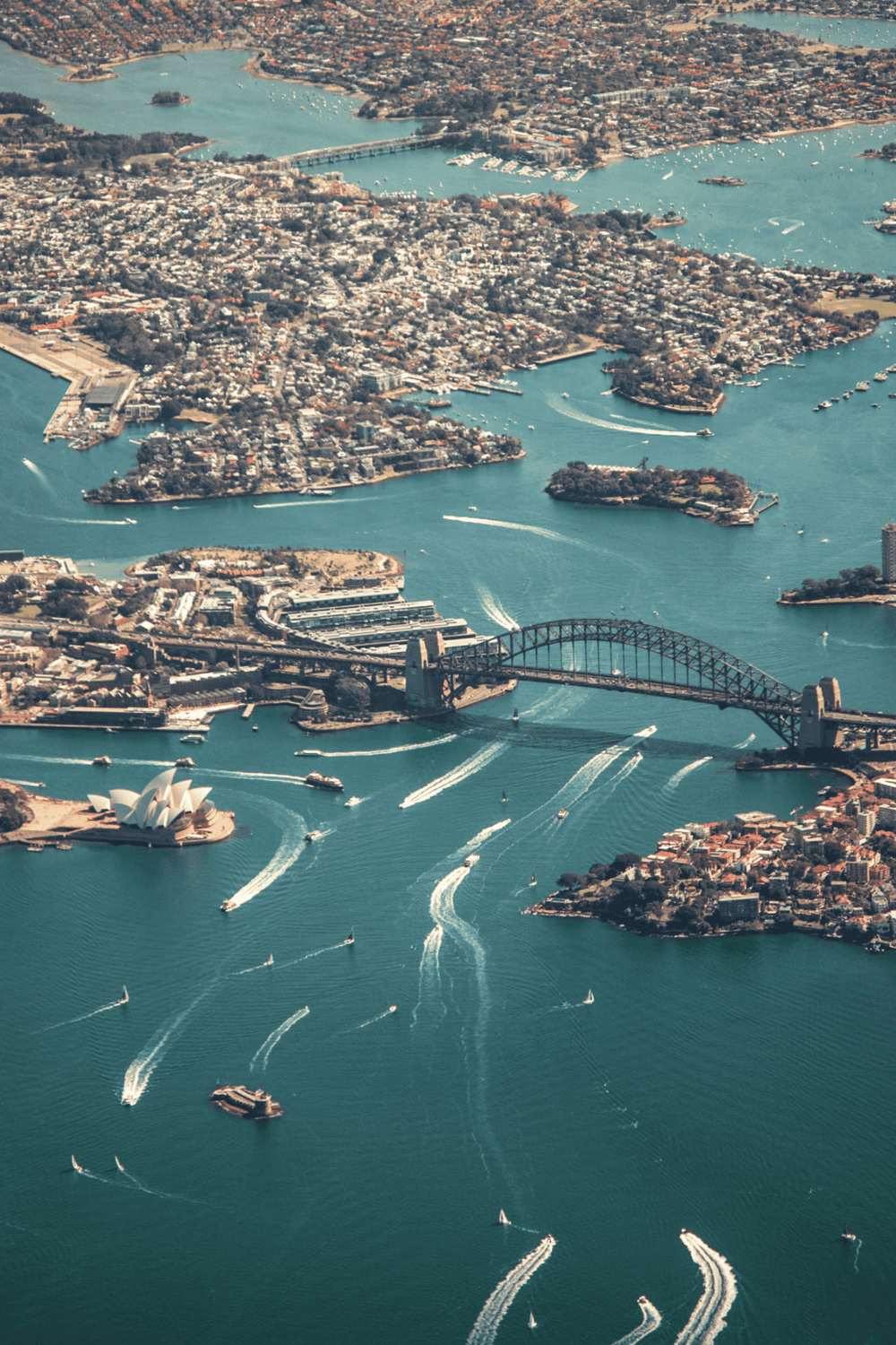 Aerial view of Sydney Harbour showing Boats near Sydney Opera House and Harbor Bridge with cityscape.