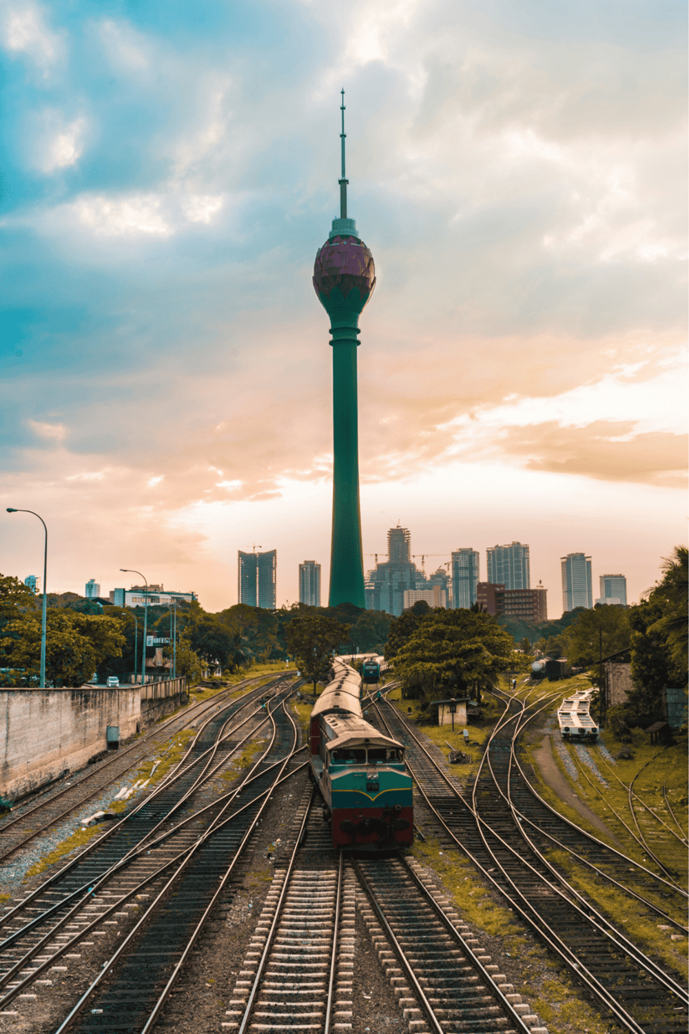 Iconic Kuala Lumpur Tower with train tracks and city skyline, showcasing transportation and urban exploration.