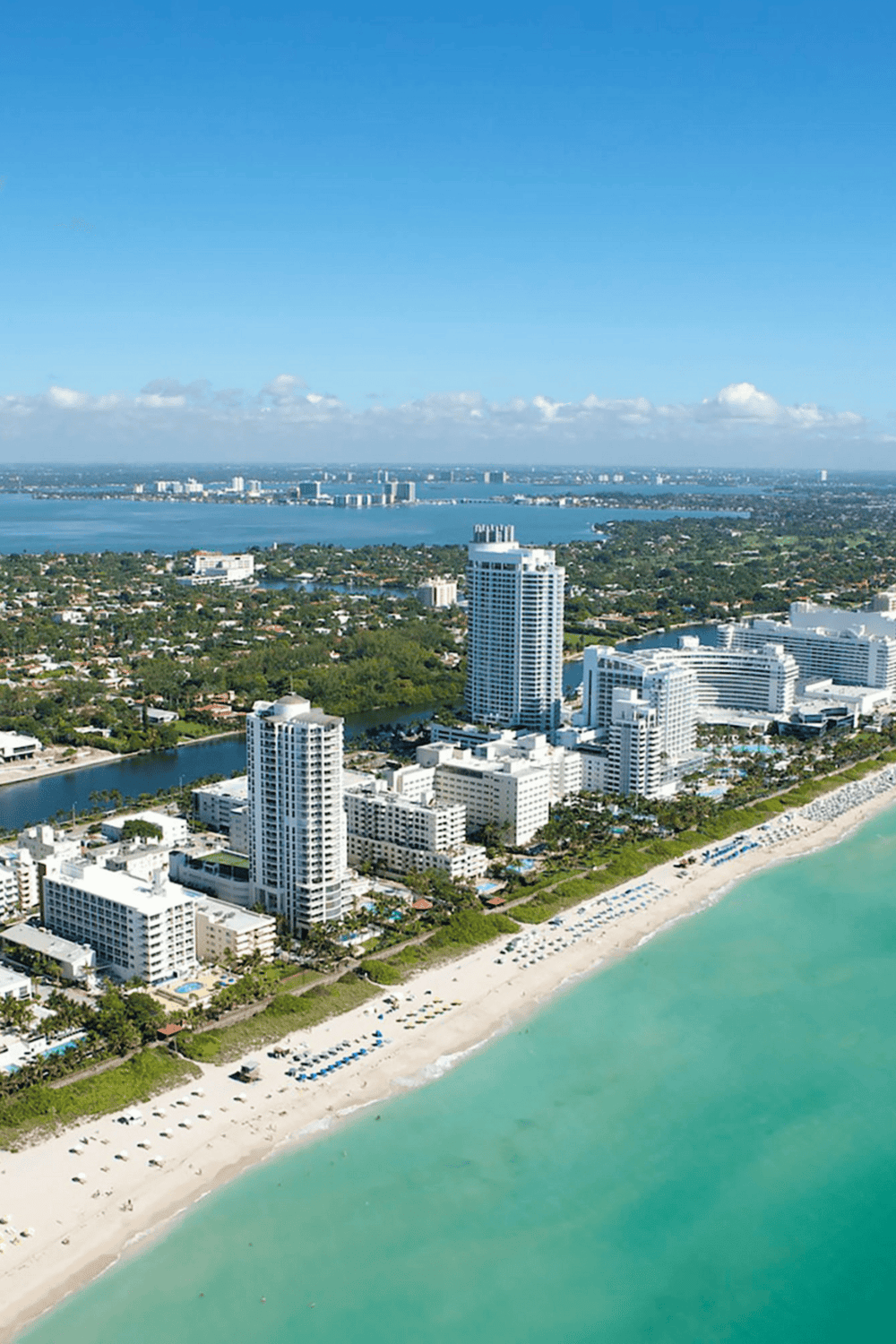 Aerial view of Miami Beach skyline with high-rise hotels and white sandy beaches.