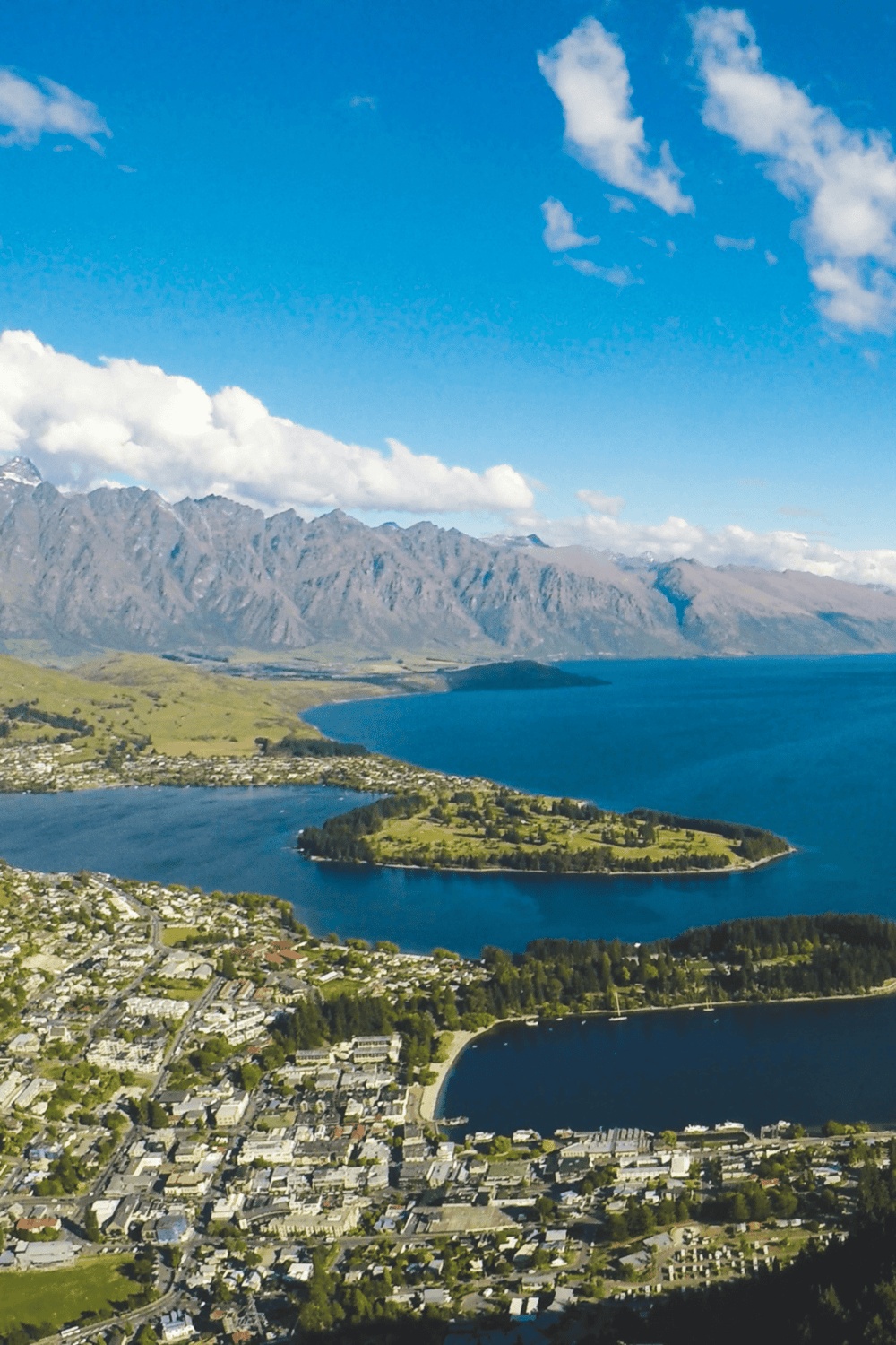 Aerial view of Queenstown New Zealand with lake, mountains, and vibrant townscape.
