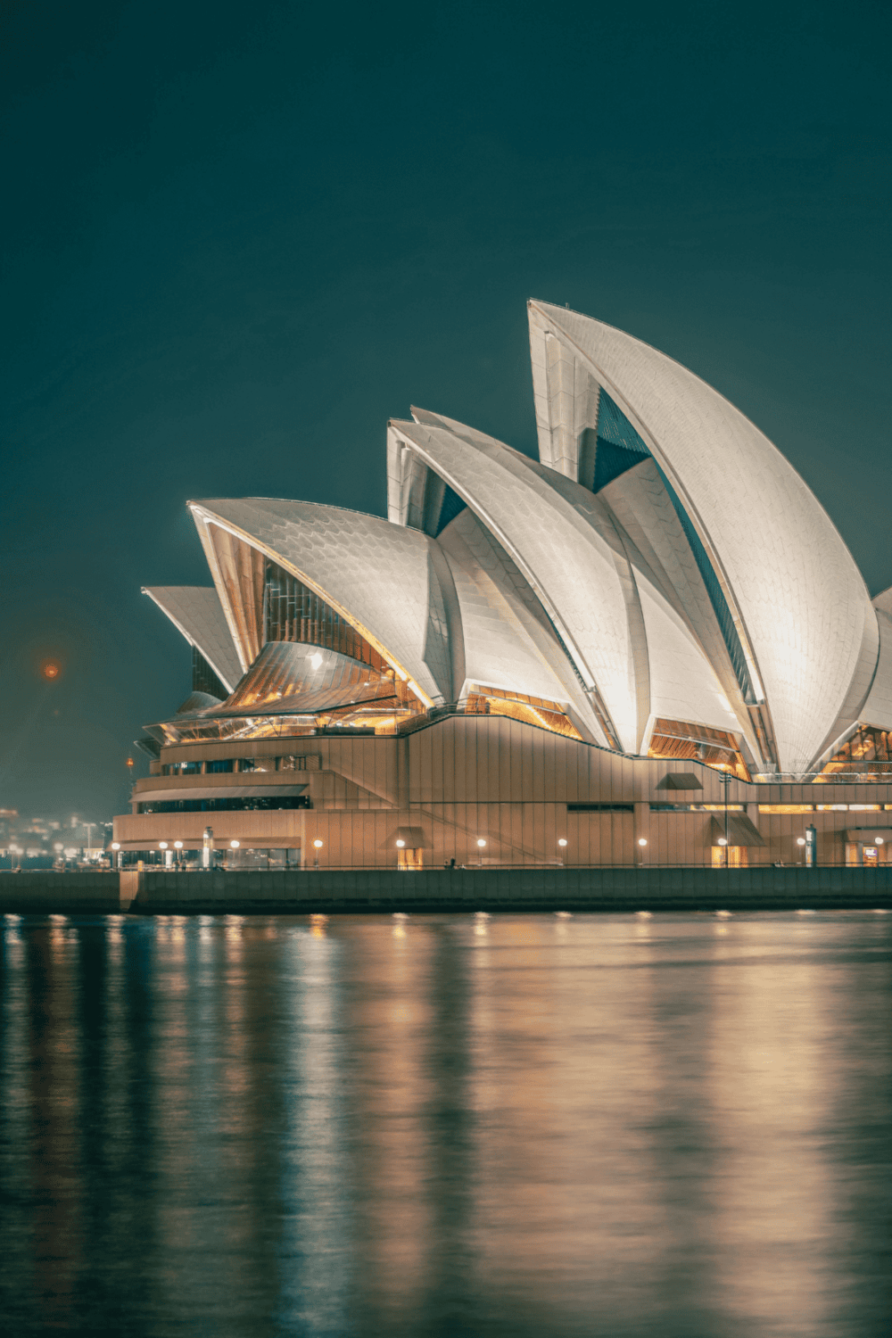 Modern Sydney Opera House at night with reflections on water, iconic landmark, travel, tourism.