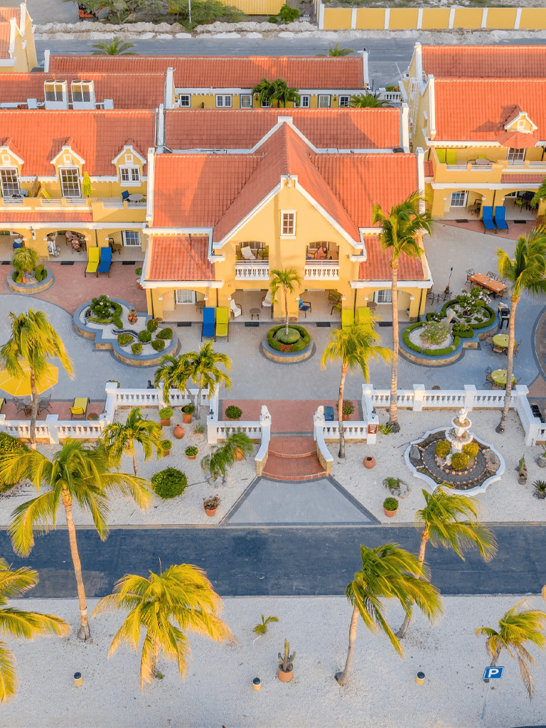 Lush tropical courtyard with yellow villas and palm trees at Quest for Directions resort.