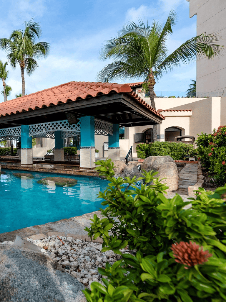 Luxury resort pool with palm trees and tropical landscaping.