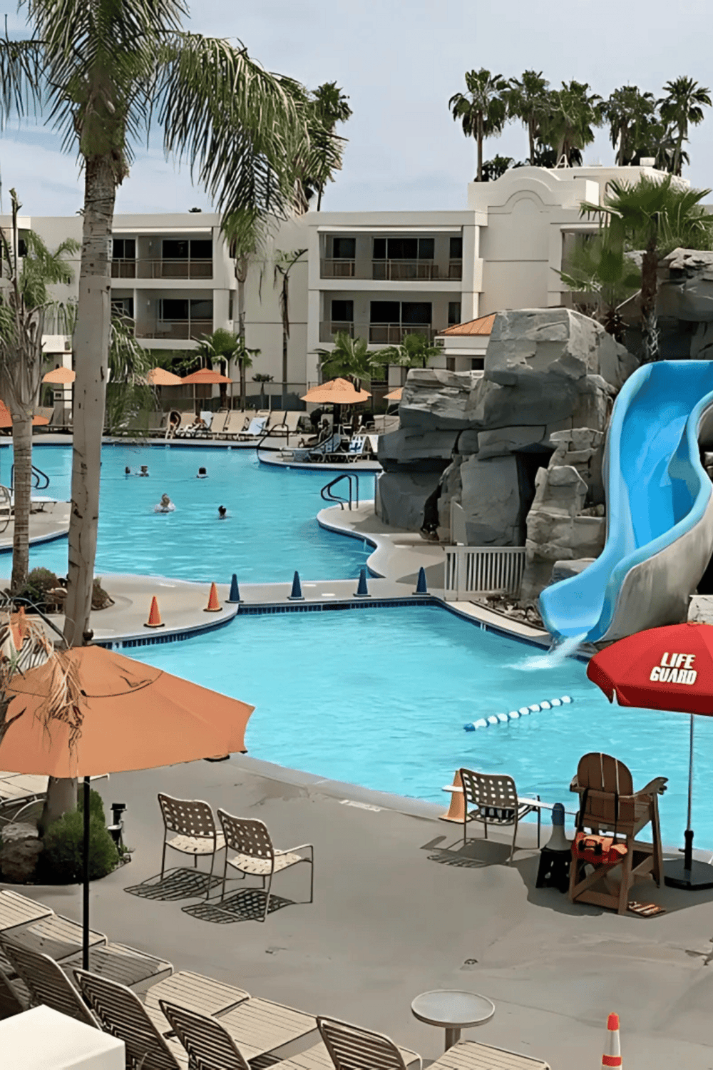 Bright poolside area at QuestForDirections resort with water slide, lounge chairs, and tropical palm trees.
